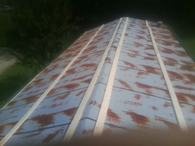Rusted metal roof panels with new wood purlins before replacement — Storm Damage Roof Repair in Leon by Roofing Brothers