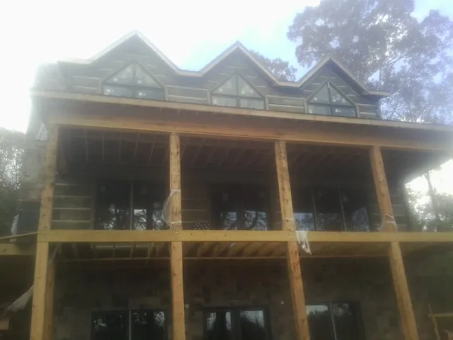 Dormers and porch framing on a large log home under construction — Roof Coating work by our crew in Leon