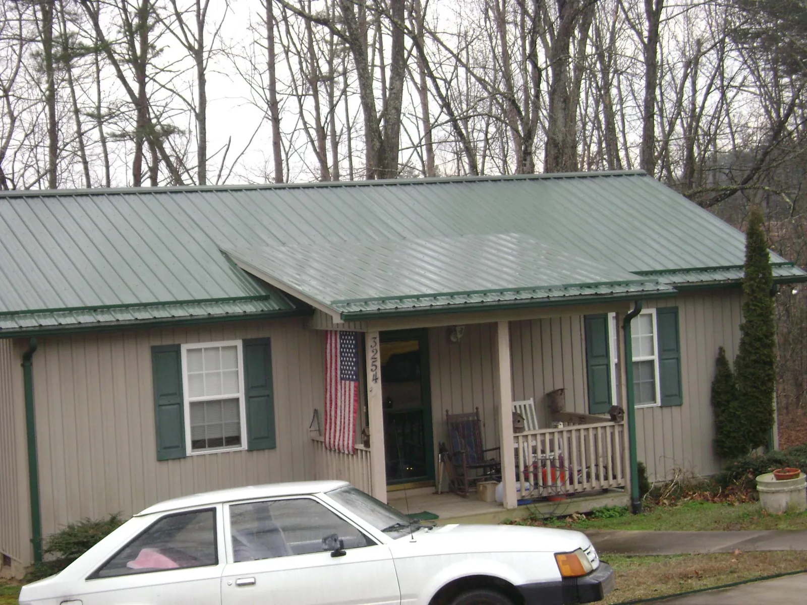 Green metal roof and front porch on a tan sided cottage in Leon