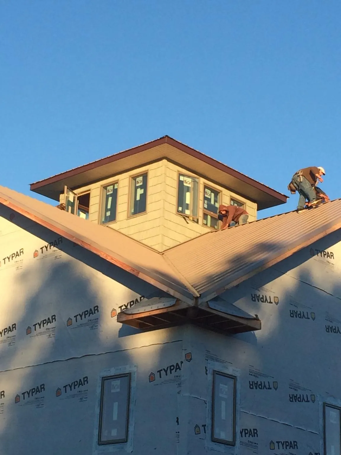 Roofers working around a rooftop cupola on a new metal roof at sunset — Roof Waterproofing in Leon by Roofing Brothers